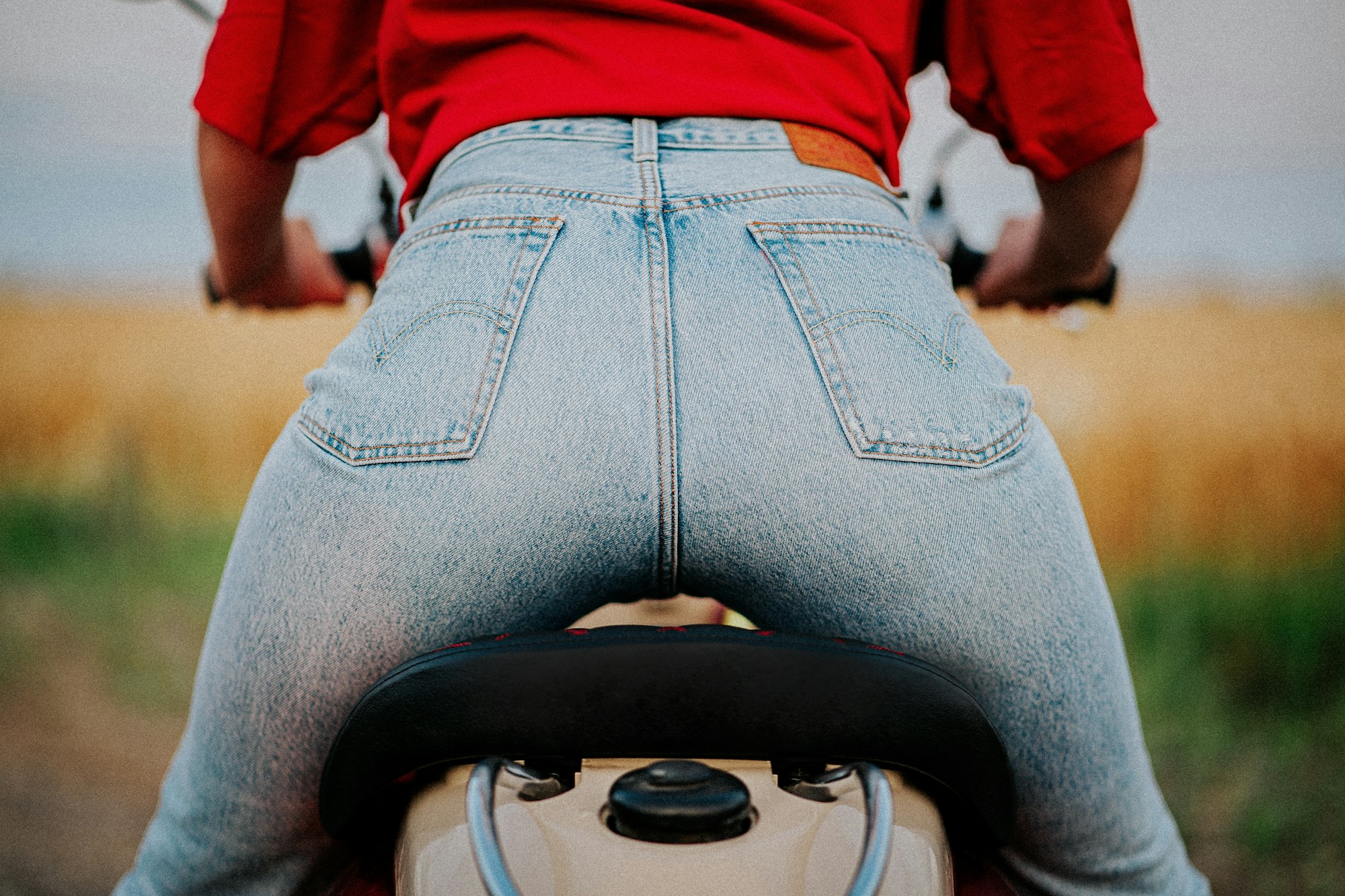 Buttocks of a young woman in stylish jeans on the seat of a motor scooter. back view. sexy ass.
